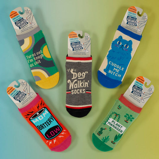 Five pairs of colorful socks with humorous phrases, arranged in a circle on a blue and green background. Each sock has a unique design and playful text.