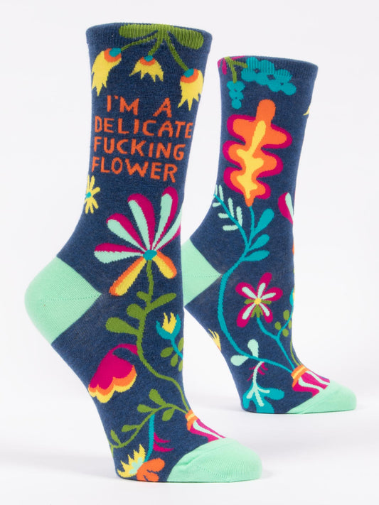 Blue Q's "I'm A Delicate Fucking Flower" W-Crew Socks feature navy blue fabric with colorful floral designs, bold orange lettering, and light green heels, toes, and cuffs for a comfy, stylish touch.
