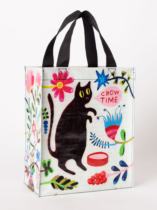 The Blue Q "Chow Time Handy Tote" is a colorful reusable bag with a black cat, flowers, kibble, and "Chow Time" in a speech bubble. Sturdy black handles make it perfect for any feline fan.