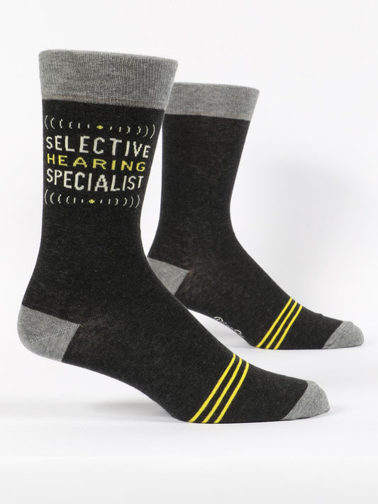 Blue Q's Selective Hearing M-Crew Socks feature black and gray combed cotton, gray toes, heels, and cuffs, yellow stripes by the ankles, and "SELECTIVE HEARING SPECIALIST" text on the upper calf in yellow and white.