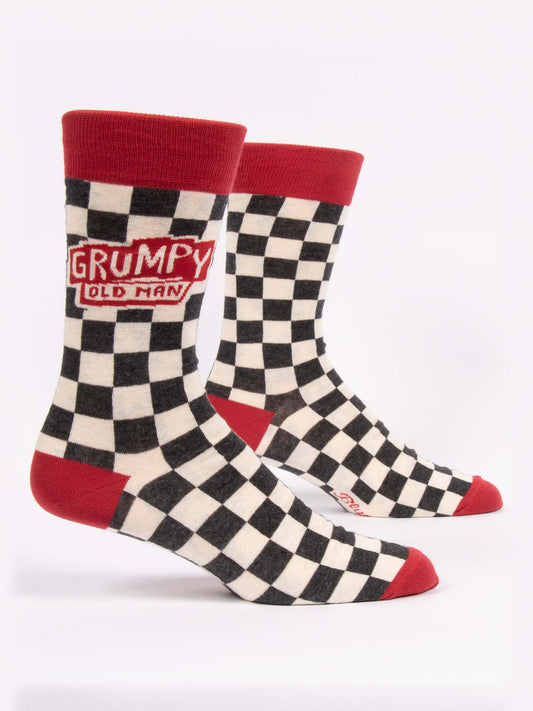 Blue Q Grumpy Old Man M-Crew Socks feature a black-and-white checkered design with red cuffs, heels, and toes, plus a playful red patch reading “GRUMPY OLD MAN” in white text.