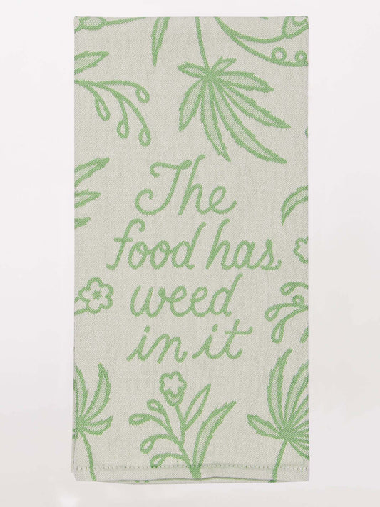 The Food Has Weed In It Dish Towel by Blue Q features a beige color with green embroidery, leafy designs, and the phrase "The food has weed in it"—a fun kitchen accessory for those who like to add some love to their cooking.