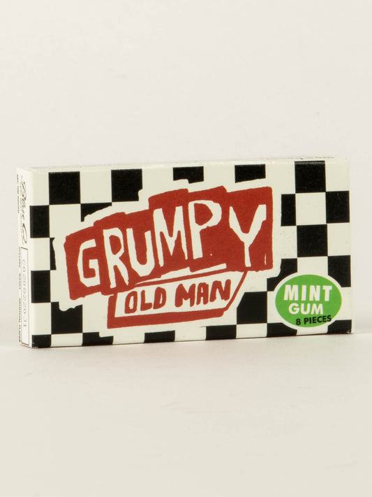 A box of Blue Q’s Grumpy Old Man Gum features a black and white checkered design, bold red and white “Grumpy Old Man” lettering, and a green circle stating “Mint Gum 8 pieces.”.
