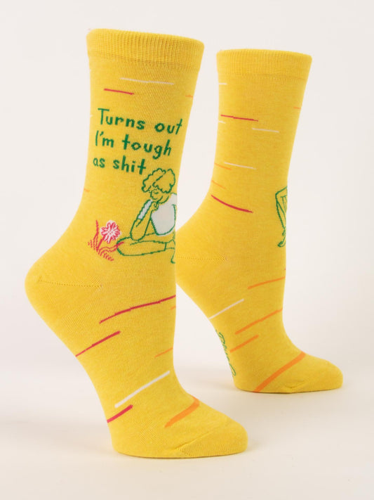 Blue Q’s “Turns Out I’m Tough As Shit” W-Crew Socks feature soft yellow combed cotton, a cartoon figure sitting by a flower, and bold green text. Red and white lines add flair to these fun, comfy crew socks.