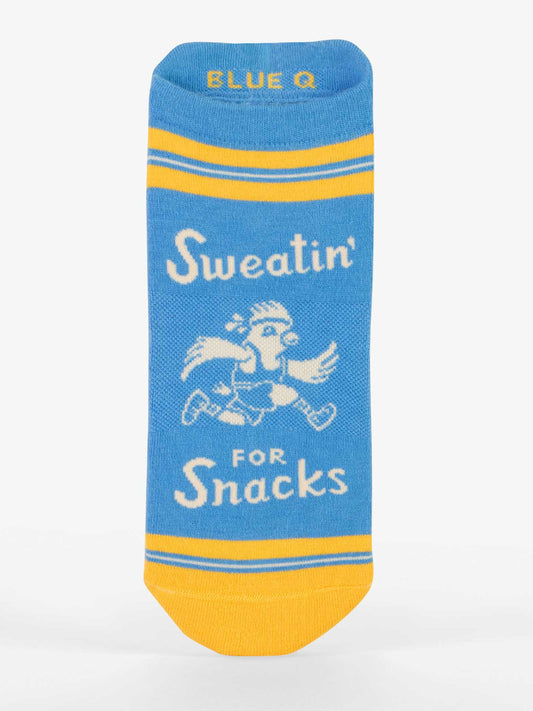 Blue Q’s Sweatin' For Snacks Sneaker Socks feature a blue design with yellow stripes and toe, a cartoon bird running with food, and the text "Sweatin’ for Snacks." These cushioned athletic socks add comfort to every stride.