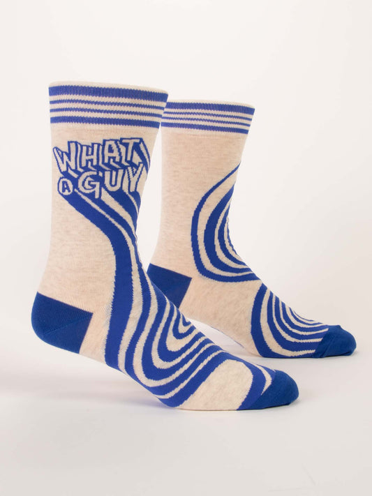 Blue Q What A Guy M-Crew Socks: Cream-colored, made from soft combed cotton, feature bold blue stripes, unique patterns, and "WHAT A GUY" in large blue letters near the top.