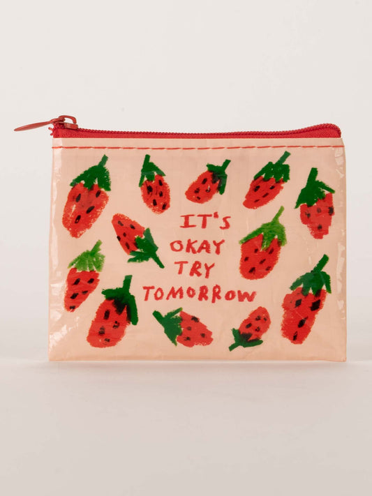 The Blue Q "It's Okay Try Tomorrow Coin Purse" is a small beige pouch with hand-drawn strawberries and “ITS OKAY TRY TOMORROW” in red and green on the front.
