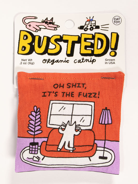 Blue Q Busted! Oh Shit, It's The Fuzz! Catnip Toy features a cartoon cat spying a police car, with "OH SHIT, ITS THE FUZZ!" text. Contains premium organic catnip grown in the USA for healthy play.