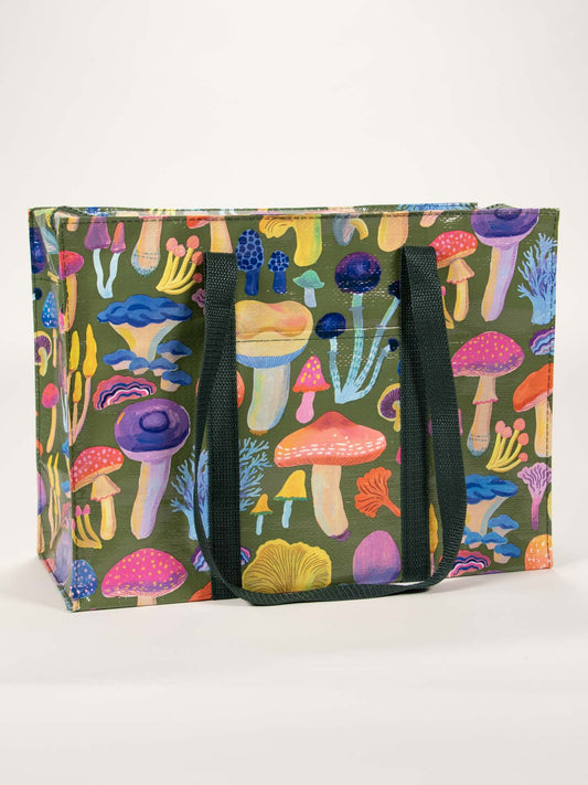 The Mushrooms Shoulder Tote by Blue Q features black handles and playful mushroom art on green, making it a charming reusable travel accessory for your next security checkpoint.