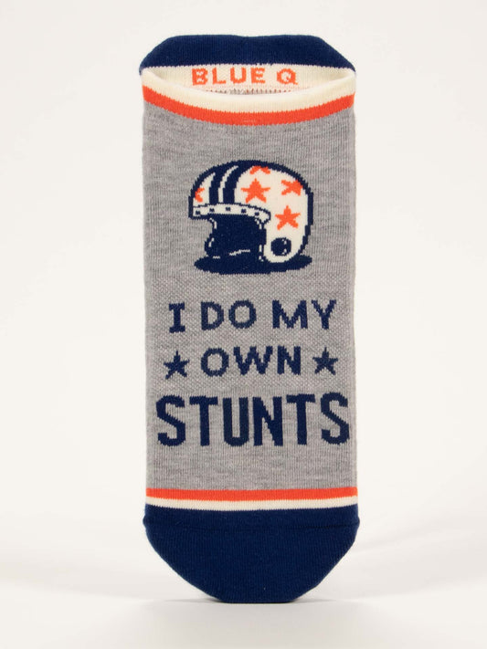 Blue Q’s I Do My Own Stunts Sneaker Socks are gray with navy and orange stripes, a retro helmet with stars, bold “I do my own stunts” lettering, and a shock-absorbing cushion for comfort.