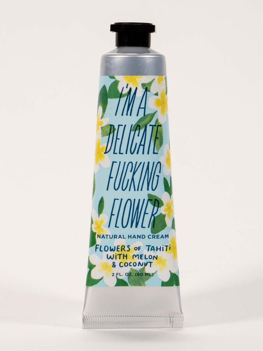 A 2 fl. oz. (60 mL) tube of Blue Q's "I'm A Delicate Fucking Flower Hand Cream Flowers Of Tahiti With Melon & Coconut," featuring shea butter and a floral design.