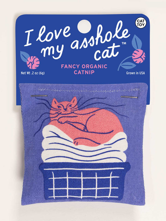 The Blue Q "I Love My Asshole Cat" Catnip Toy comes in a blue package with white text, featuring an orange cat on towels in a laundry basket. It contains organic catnip to encourage healthy play.