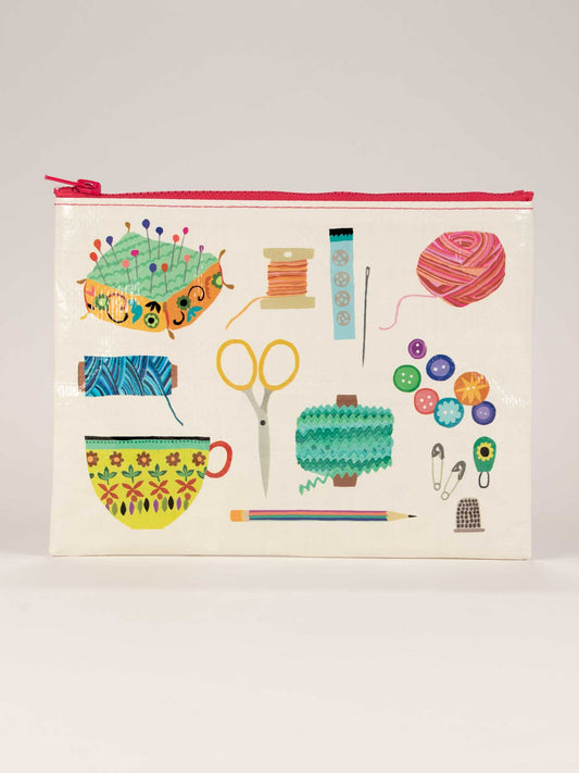 The Blue Q Sewing Kit Zipper Pouch features a white design with a red zipper and colorful sewing motifs—ideal for organizing your mending essentials or clear nail polish.