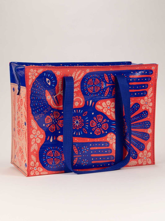 The Blue Q Rare Bird Shoulder Tote is a reusable bag with blue handles, showcasing a vibrant peacock and floral design on an orange and pink background, inspired by Stresemann's Bristlefront—one of the world’s rarest birds.