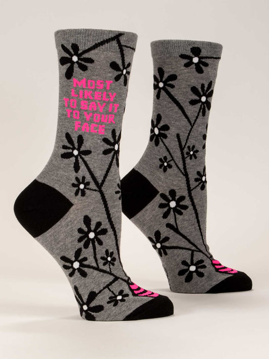 Blue Q’s "Most Likely To Say It To Your Face" W-Crew Socks are gray combed cotton with black toe, heel, and flower designs. Pink text on one sock reads “MOST LIKELY TO SAY IT TO YOUR FACE.”.