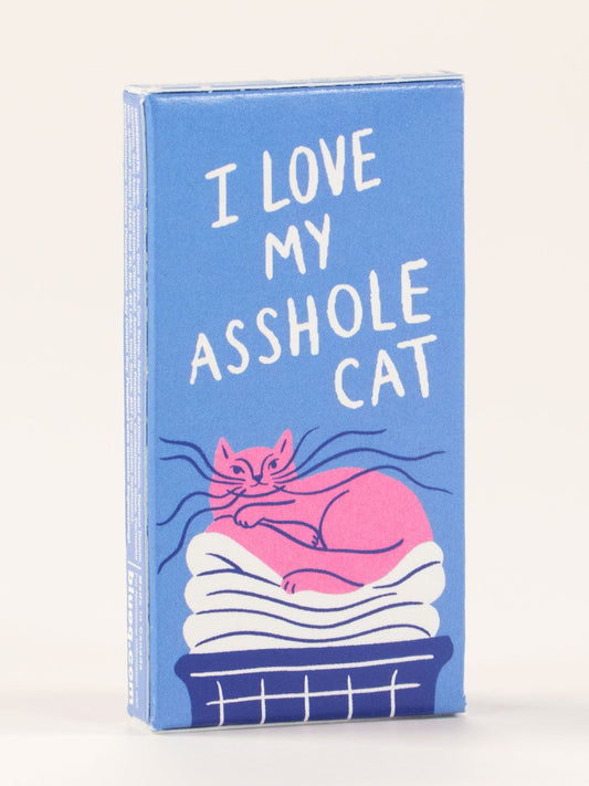 A blue box of Blue Q's "I Love My Asshole Cat Gum," featuring a pink cat lounging on white laundry—an ideal cat-themed gift for feline fans.
