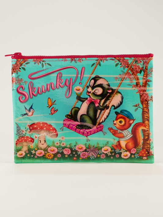 The Skunky Zipper Pouch by Blue Q showcases a cartoon skunk on a swing with “Skunky!” in pink above, surrounded by a squirrel, flowers, butterflies, mushrooms, and a bird on a vibrant turquoise background.