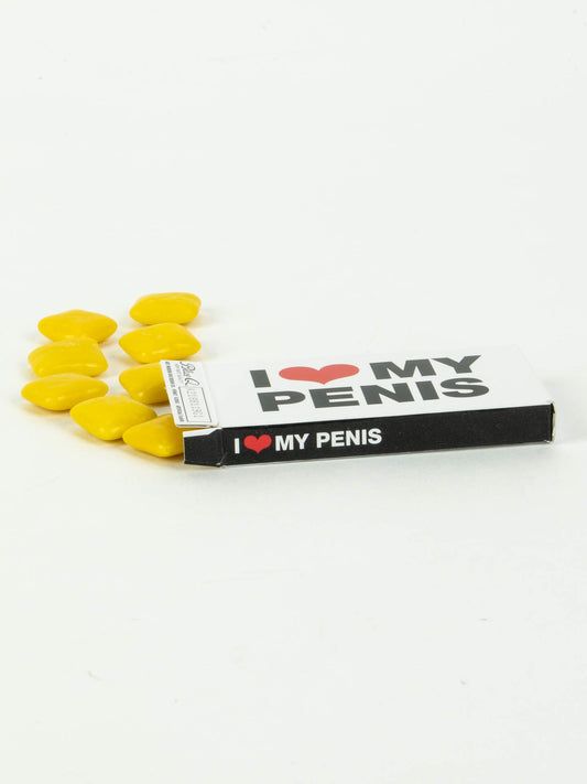 A box of Blue Q’s I Heart My Penis Gum sits open on a white surface, with several yellow, candy-coated, heart-shaped pieces spilling out—there are 8 pieces per box.