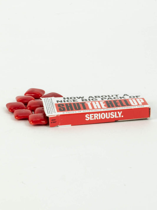 Blue Q's Shut The Hell Up Gum—a funny novelty pack of red cinnamon gum—spills from a box on a white background, labeled "HOW ABOUT A NICE BIG PIECE OF SHUT THE HELL UP SERIOUSLY.