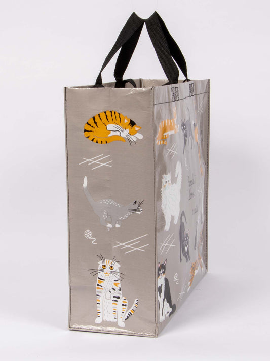 The Blue Q "People I Love: Cats Shopper" is a reusable bag with black handles, featuring colorful cat illustrations on a light gray background—perfect for showing off your love of cats wherever you go.