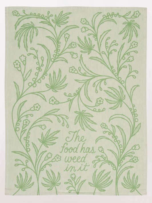 The Food Has Weed In It Dish Towel by Blue Q features beige cloth with light green embroidered botanical designs and the phrase “The food has weed in it”—a playful, stylish addition to any kitchen.