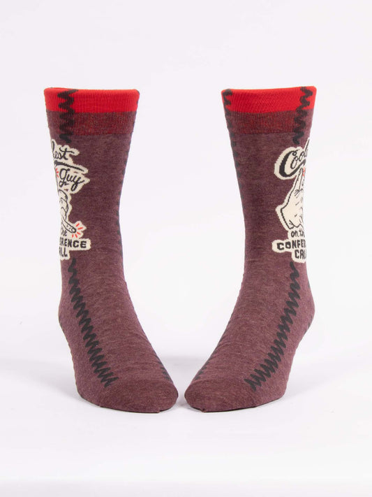 Blue Q’s Coolest Guy On The Conference Call M-Crew Socks are brown combed cotton socks with red cuffs, black zigzag sides, and a white graphic with text and an illustrated face—fun novelty workplace gift socks.