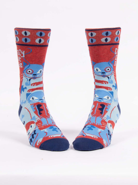 The Blue Q Crazy Cat Dude M-Crew Socks feature bold blue and red cartoon cats, a repeating eye pattern, and "CRAZY CAT DUDE" on the side. Made from soft combed cotton, these novelty socks are perfect for cat lovers.