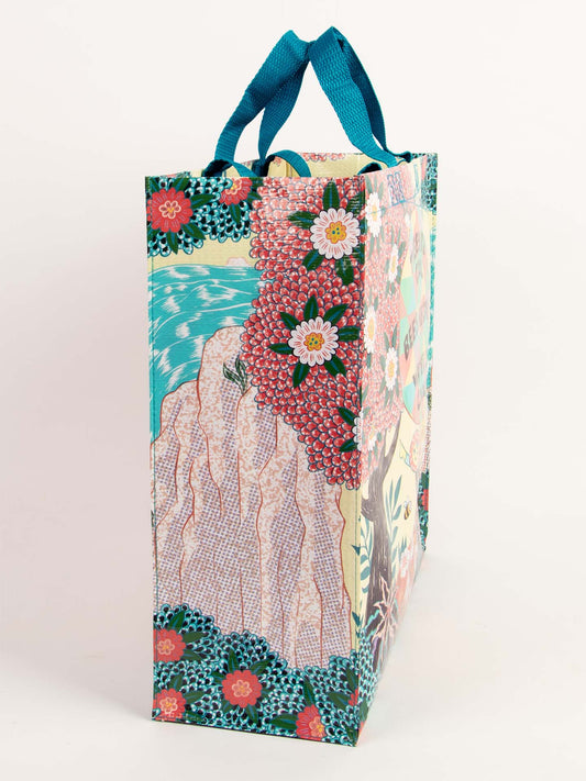 The Blue Q "Trees Are Cool. Bees Are Cool. Water Is Cool." Shopper is a colorful reusable bag with blue handles, featuring charming illustrations of nature and creatures that celebrate earth’s beauty on a white background.