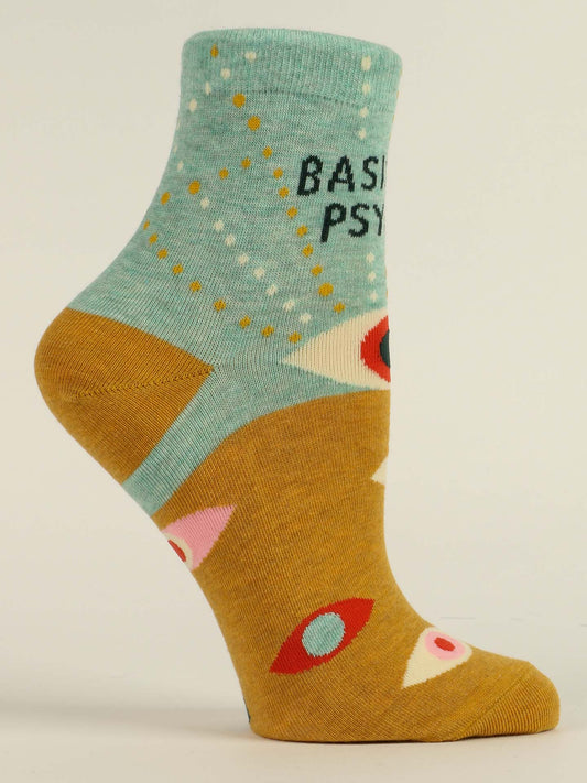 The Blue Q Basically Psychic W-Ankle Socks feature abstract eyes, dots, and geometric shapes in teal, mustard yellow, red, white, and pink. The phrase "BASIC PSY" appears near the top.