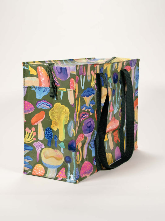 The Blue Q Mushrooms Shoulder Tote is a reusable shopping bag with black handles and a colorful illustrated mushroom pattern on dark green—a perfect travel accessory for quick trips or the security checkpoint.