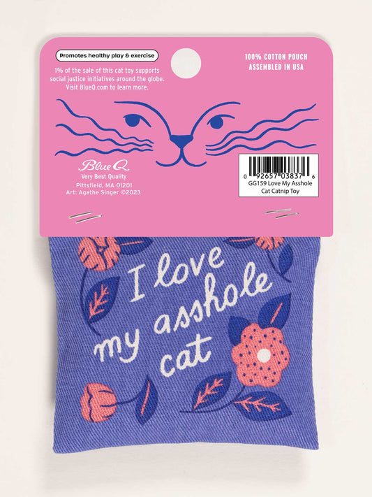 The Blue Q "I Love My Asshole Cat" Catnip Toy is a purple pouch with pink and orange flowers, stitched text, and pink packaging with a minimalist cat face. Filled with organic catnip for healthy play your cat will love.