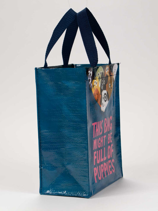 The Blue Q "This Bag Might Be Full Of Puppies" Handy Tote is a blue reusable bag with cartoon puppies, dark blue handles, and pink text—ideal for puppy lovers. Available for just $50!.