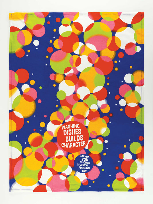 The Blue Q "Washing Dishes Builds Character. Maybe You Should Give It A Fucking Try." Dish Towel features overlapping red, orange, pink, green, and white circles on a blue background with bold white and pink text.