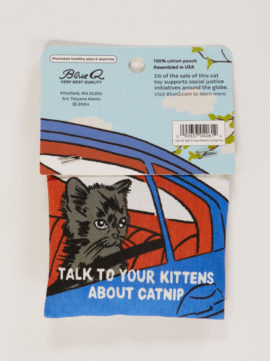 The Blue Q Talk To Your Kittens About Catnip Toy is a cotton pouch with a black kitten in a red and blue car and "TALK TO YOUR KITTENS ABOUT CATNIP." Packaging details healthy play and supports a good cause.