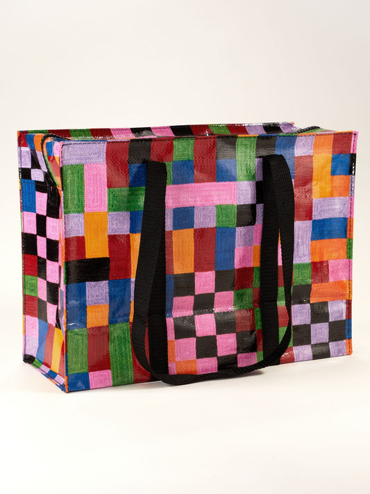 The Color Cube Shoulder Tote by Blue Q is a large reusable art bag with black handles, showcasing a vibrant patchwork of pink, orange, green, blue, purple, red, and black squares on a white background.