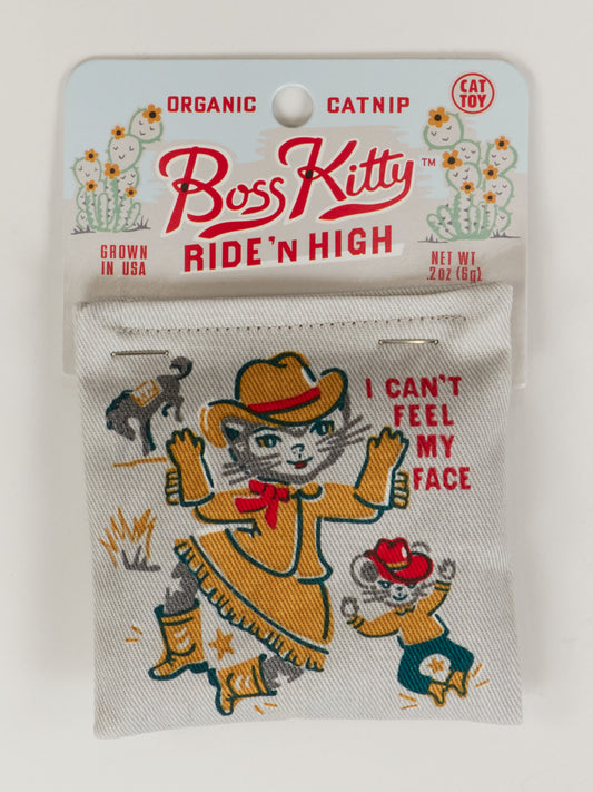 The Boss Kitty Catnip Toy by Blue Q features a cartoon cat in a cowboy hat and boots with the text "I CANT FEEL MY FACE," plus smaller animals in cowboy outfits, and offers healthy play using organic catnip.