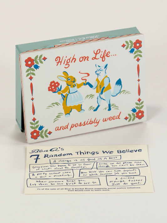 The Blue Q "High On Life...And Possibly Weed Pocket Box" features a fox and deer in clothes with the phrase above them—a playful, decorative tin. Below is Blue Q’s 7 Random Things We Believe card, filled with handwritten notes.