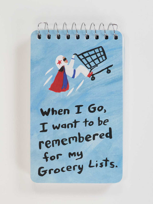 The Blue Q "When I Go, I Want To Be Remembered For My Grocery Lists" 3x5 Spiral Notebook features a superhero in a shopping cart and celebrates your grocery lists as everyday epics.