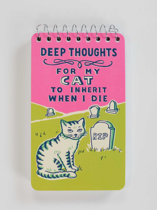 The Blue Q "Deep Thoughts For My Cat To Inherit When I Die" 3x5 Spiral Notebook features a pink and green cover with Mittens the cat beside tombstones, one labeled RIP next to an old blanket. The cover bears a humorous inheritance message.