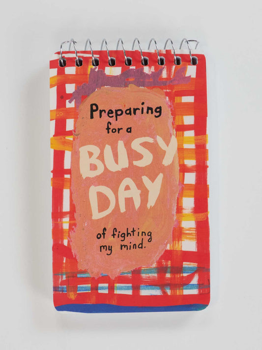 The Blue Q "Preparing For A Busy Day Of Fighting My Mind" 3x5 spiral notebook features a vibrant red, orange, and white cover design.