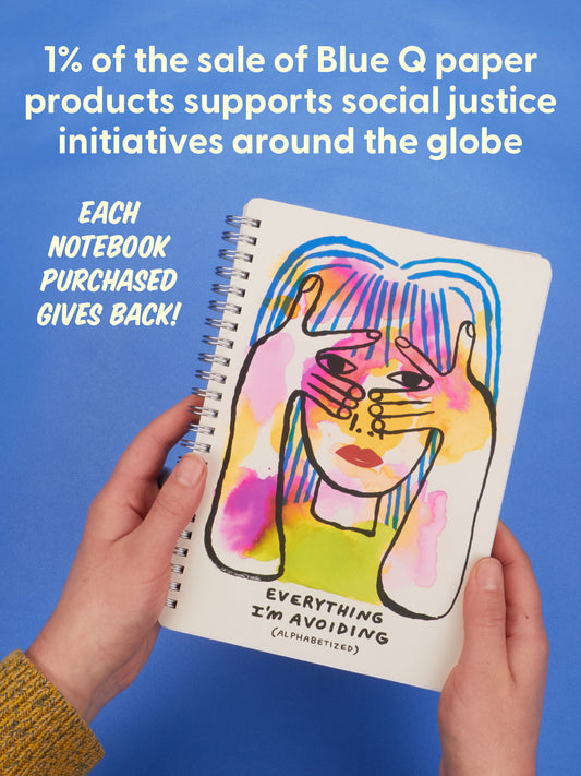 Hands holding the Blue Q “Everything I’m Avoiding (Alphabetized)” 6x8 Spiral Notebook, featuring colorful abstract art of a person covering their face, organized by color; text above reads that Blue Q donates 1% of sales to social justice initiatives.