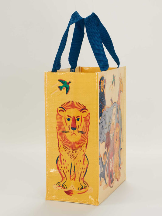 The Blue Q Animal Family Handy Tote is a yellow reusable bag with blue handles, featuring colorful illustrations of a lion and cute animals on one side, and various jungle creatures like a monkey, birds, and a fox on the other.