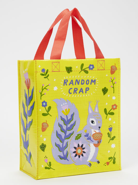 The Blue Q Random Crap Handy Tote is a yellow reusable bag made from recycled material with red handles, featuring flowers, acorns, and a cartoon purple squirrel with an acorn. "RANDOM CRAP" is boldly printed above—great for organizing or storage.
