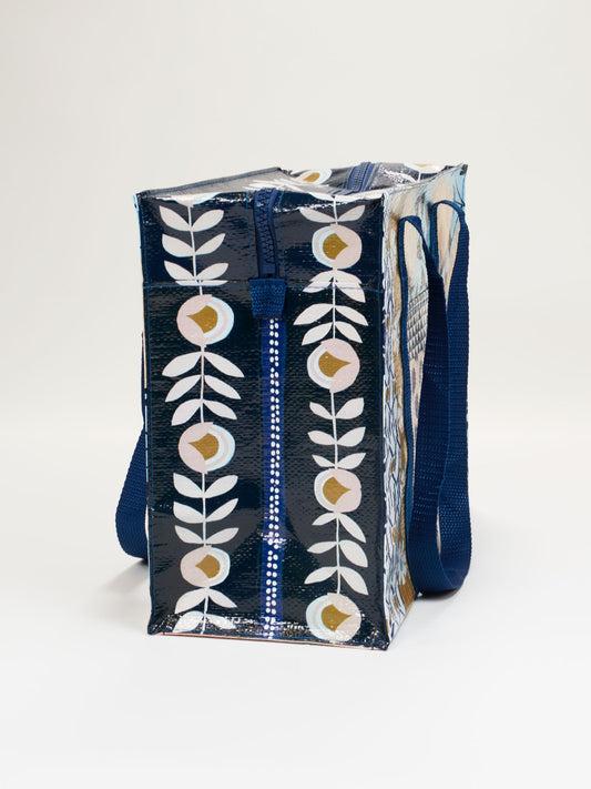 The Blue Q Patchwork Shoulder Tote features a dark blue background with a white and gold leaf pattern, durable shoulder straps, and a chunky top zipper for secure closure.
