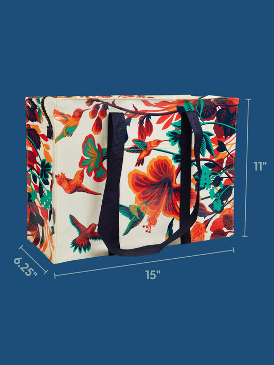 The Blue Q Hummingbird Shoulder Tote features a vibrant hummingbird and floral design, black handles, and measures 15" W x 11" H x 6.25" D. Made from recycled material, it's an eco-friendly shopping bag set against a blue background.