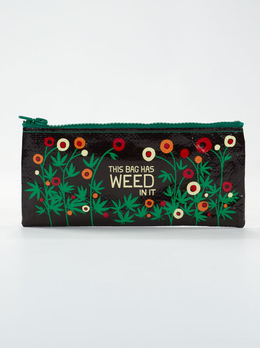 The Blue Q "This Bag Has Weed In It" Pencil Case is a black zippered pouch decorated with colorful flowers and green leaves, featuring “THIS BAG HAS WEED IN IT” in gold lettering on the front.
