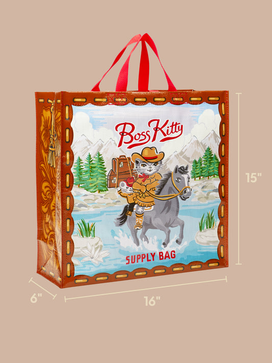 The Blue Q Boss Kitty Shopper is an eco-friendly, reusable shopping bag featuring a cartoon cat dressed as a cowboy riding a gray horse, with mountains, trees, and rivers in the background. This grocery bag measures 16 inches wide, 6 inches deep, and 15 inches tall—perfect for your daily adventures.