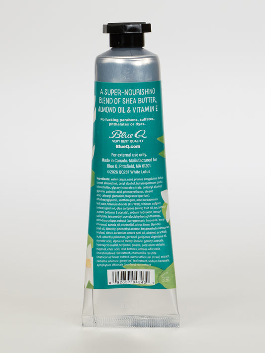 A silver and teal tube of Blue Q "I'm A Delicate Fucking Flower" Natural Hand Cream—White Lotus Flower with Bergamot & Mimosa—stands upright on a white background, its back label listing key details and ingredients.