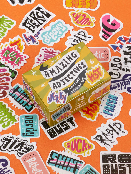 An Amazing Adjectives Playtime Sticker Set box surrounded by loose stickers featuring a collection of words in colorful fonts and graphic styles used for ascribing qualities.