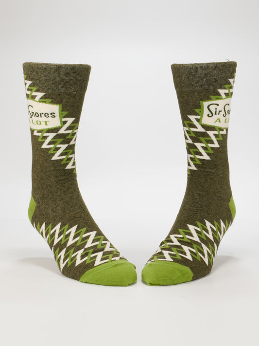 Blue Q Sir Snores A Lot M-Crew Socks, featuring green and brown nylon with zigzag patterns and "Sir Snores A Lot" on the sides, are shown upright against a white background. Fits most men's shoe sizes.